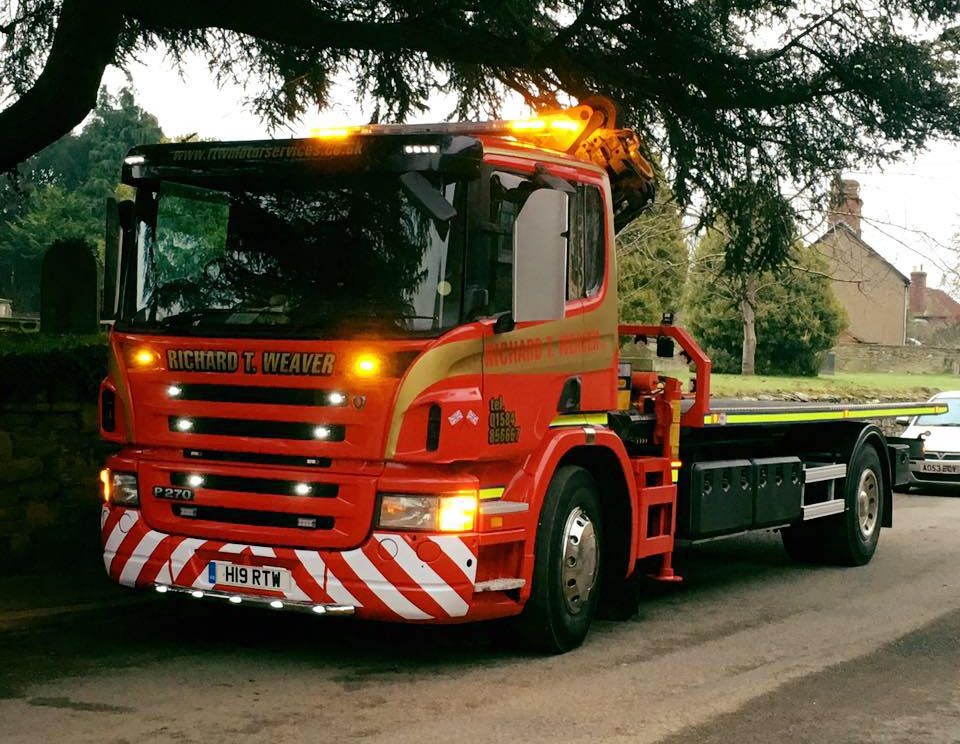 Richard T. Weaver recovery truck with its lights on, parked under a tree