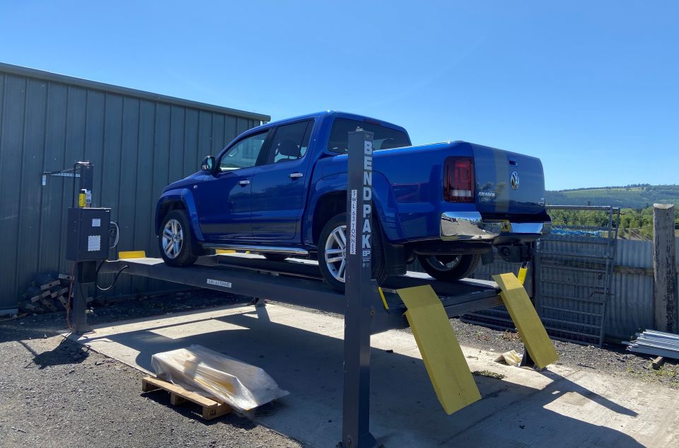 A pickup raised on a four-post lift at the garage